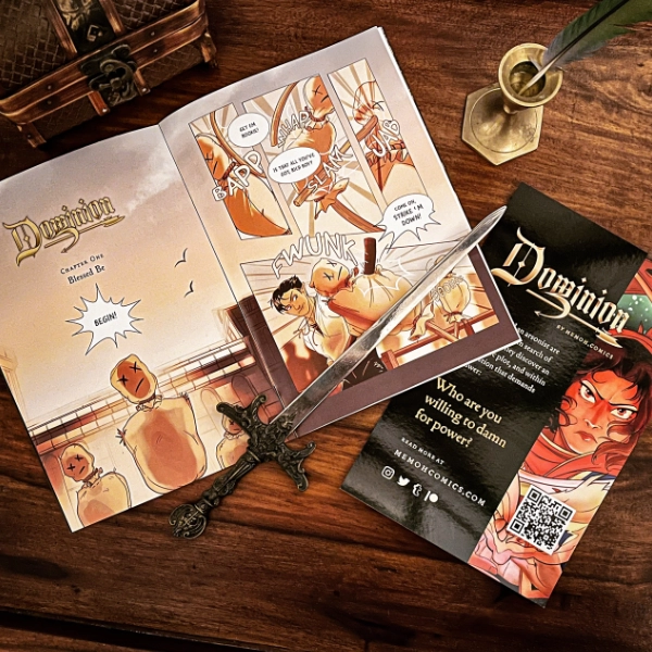 Photo of an open ‘Dominion’ comic issue next to a prop sword, a quill, a treasure box, and and advertising flyer.